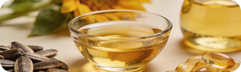 Sunflower seeds beside a small bowl of golden oil